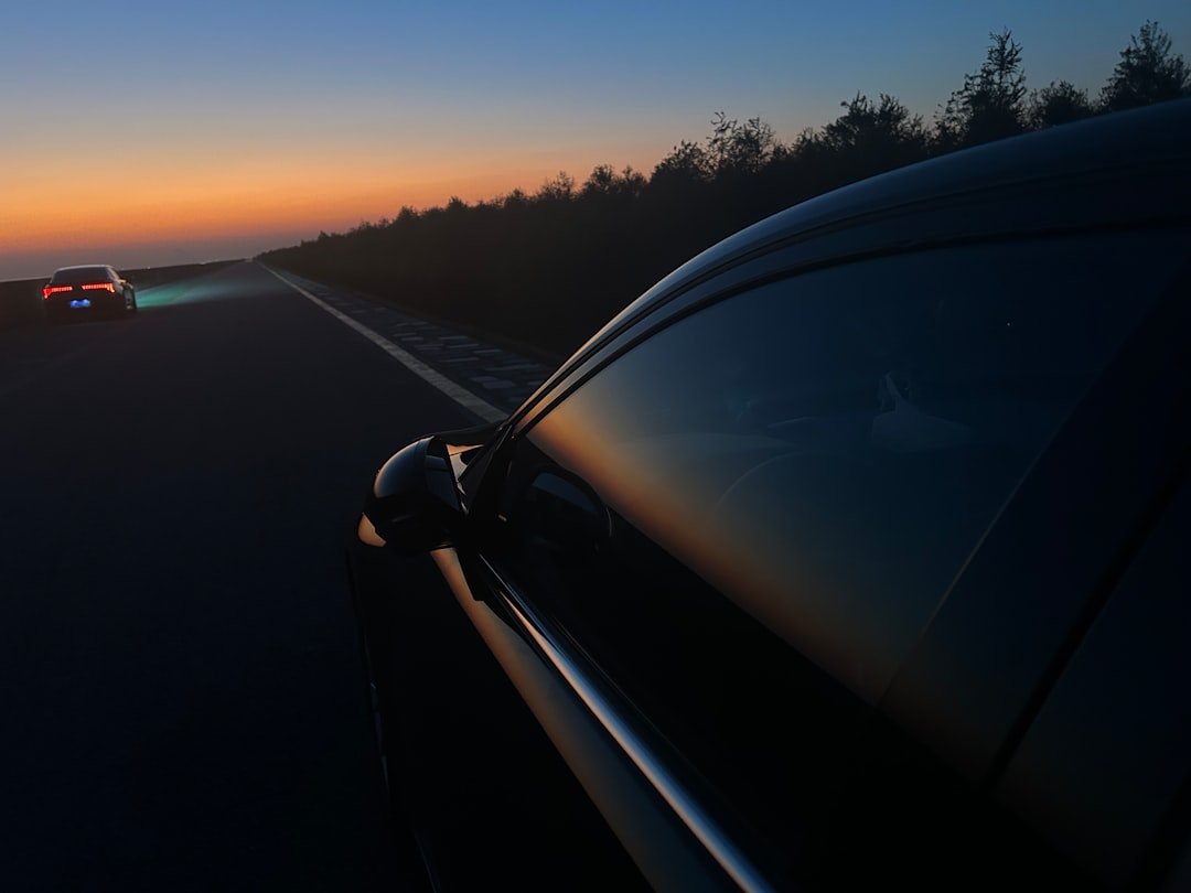 A vehicle with its headlights on driving at dusk