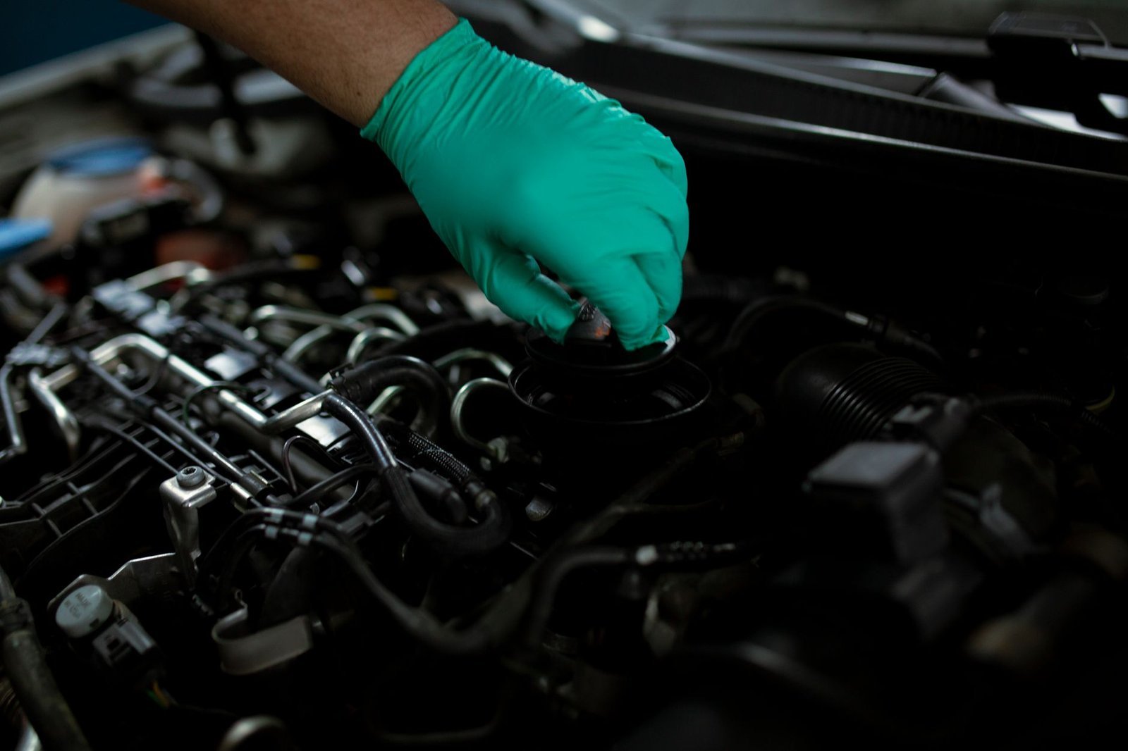 A mechanic working on an engine's cooling system cap
