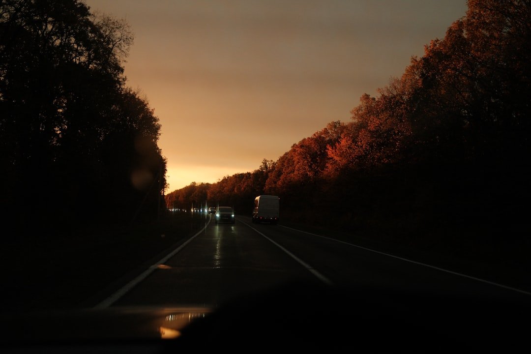 A car with headlights on during an autumn evening drive