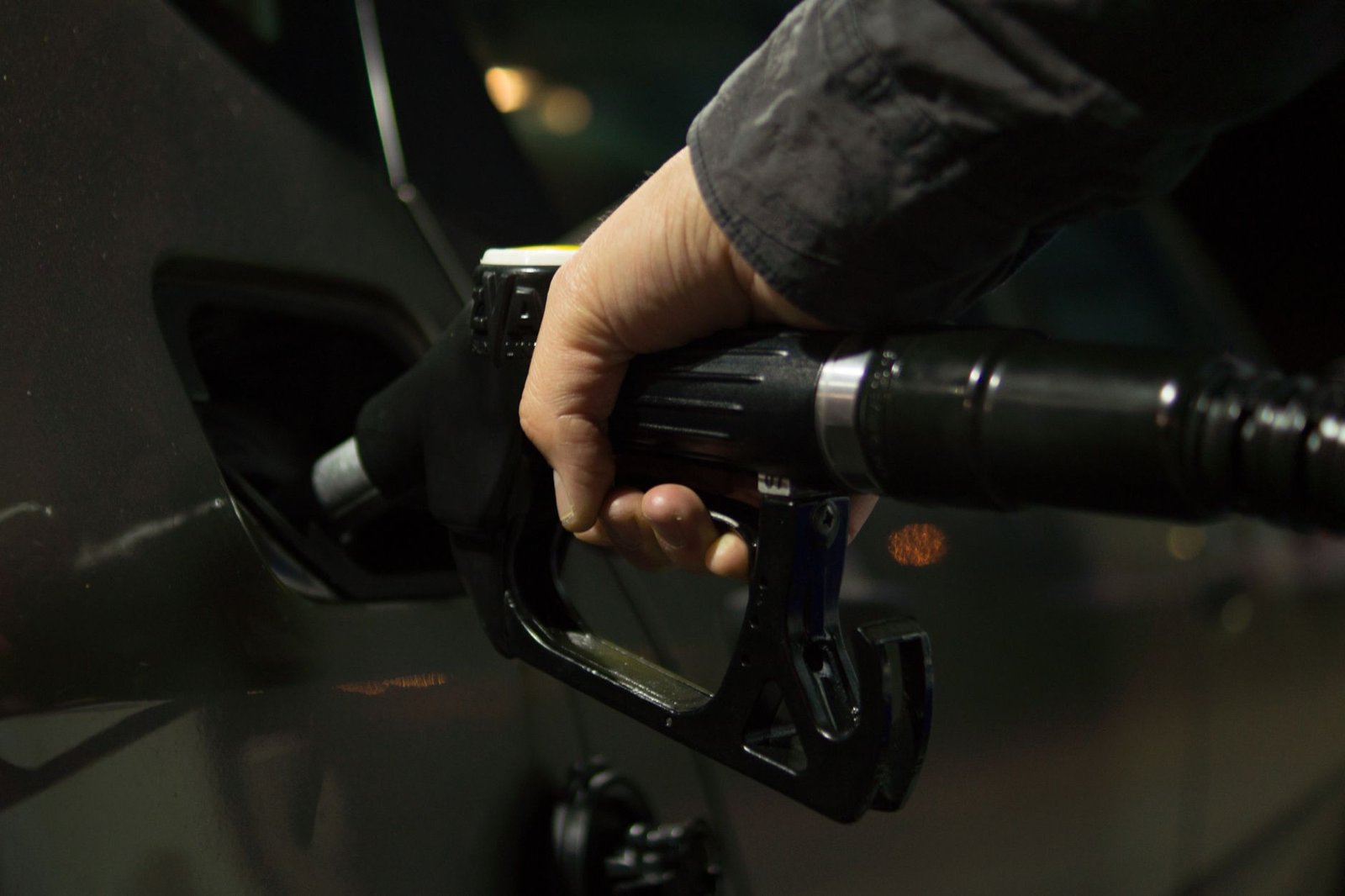 A hand holding a gas pump nozzle