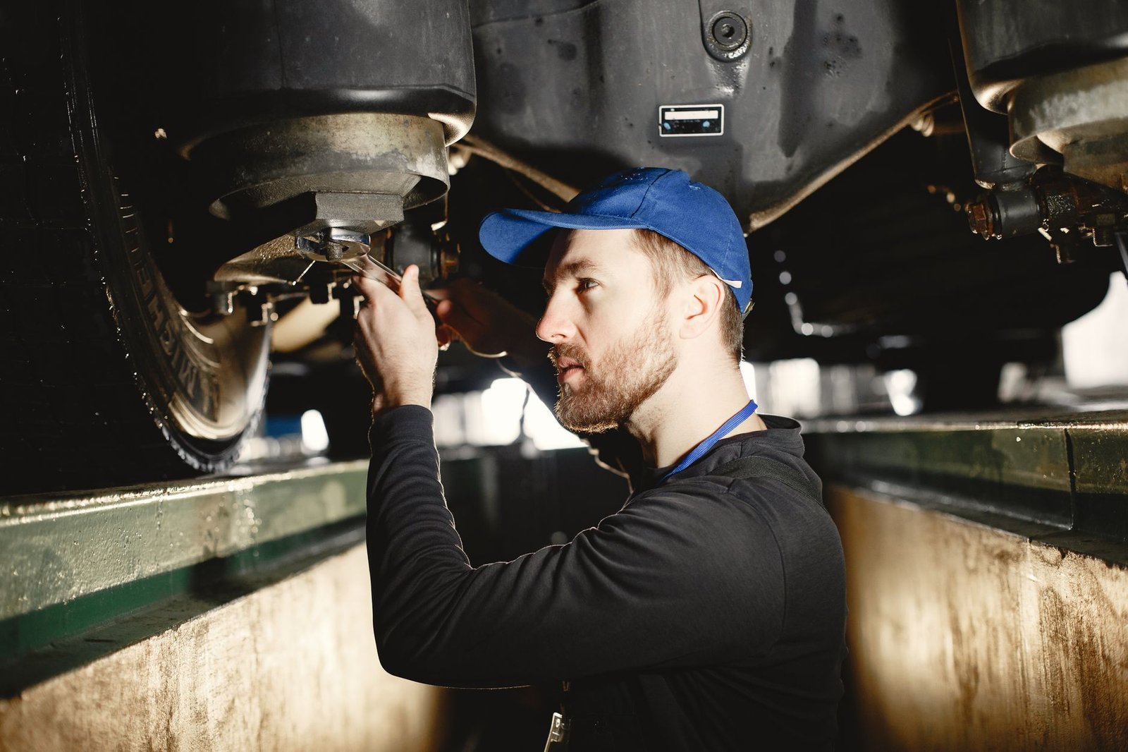 Mechanic using a wrench on a vehicle underbody component