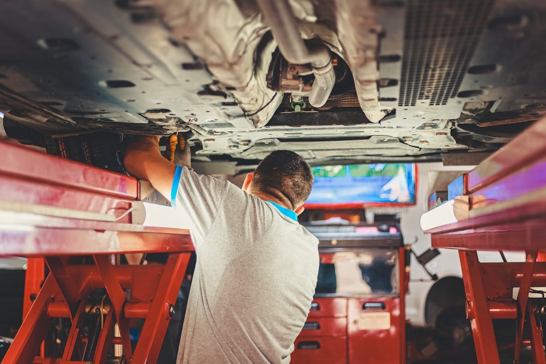 Mechanic inspecting suspension components underneath a vehicle