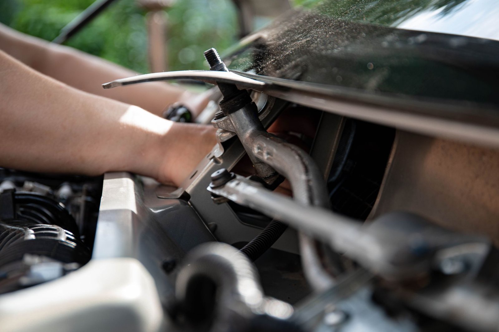 Hands working near a vehicle's cooling fan