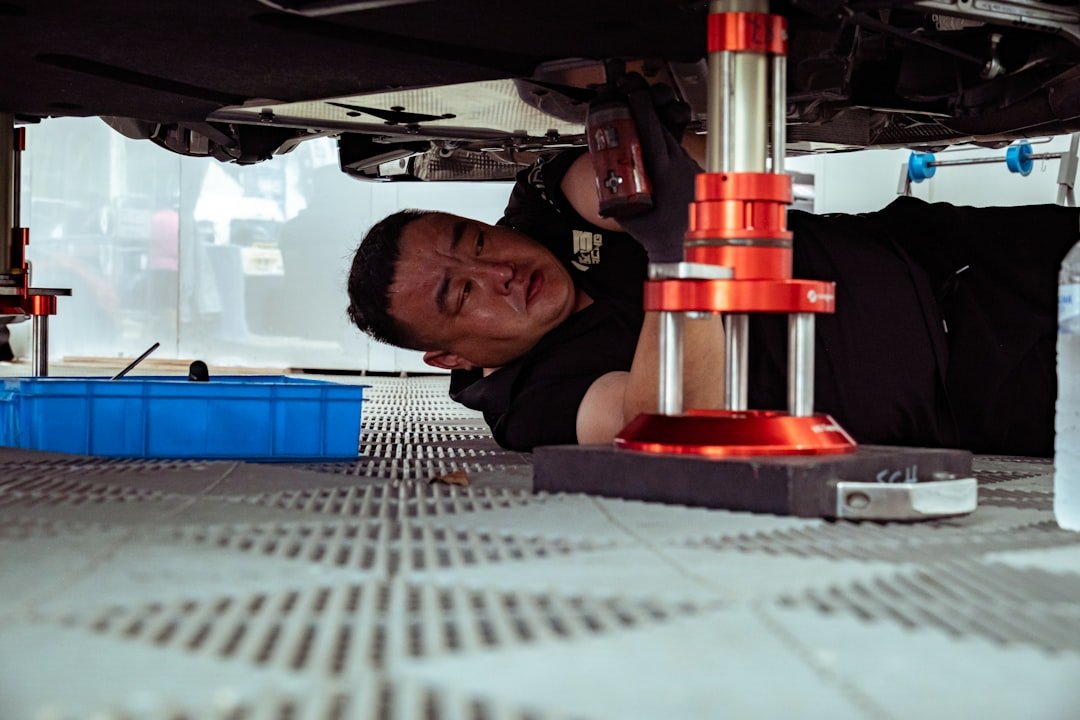 A mechanic working underneath a vehicle on a lift