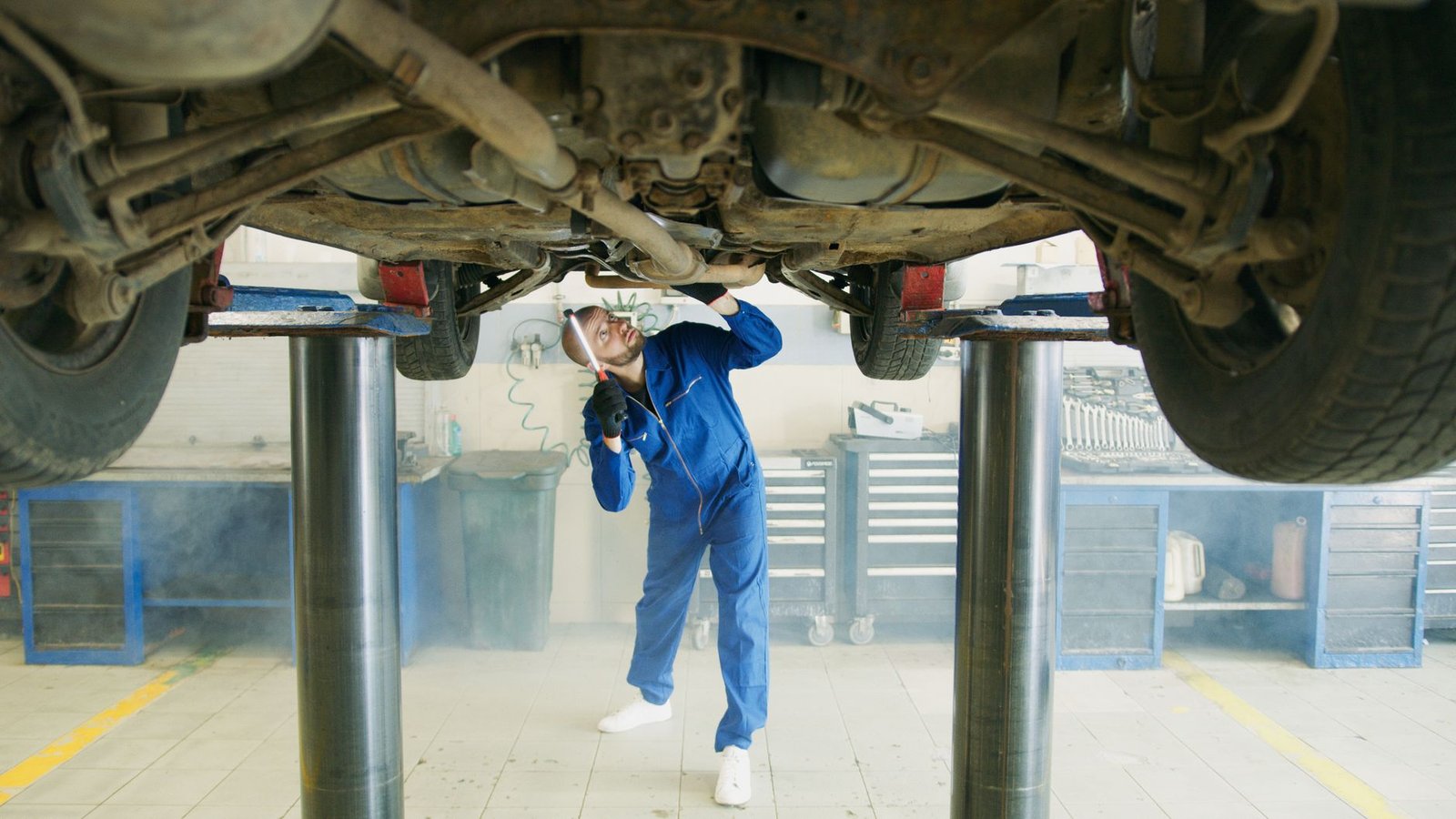 Mechanic inspecting a vehicle undercarriage on a lift