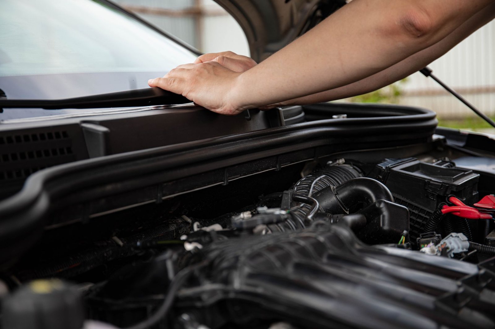 Mechanic inspecting a vehicle's front-end wiring under the hood