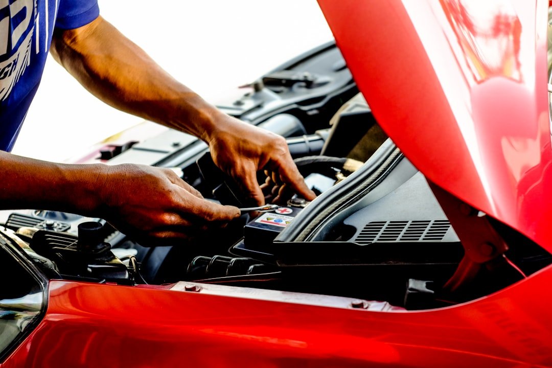 A mechanic working under an open car hood