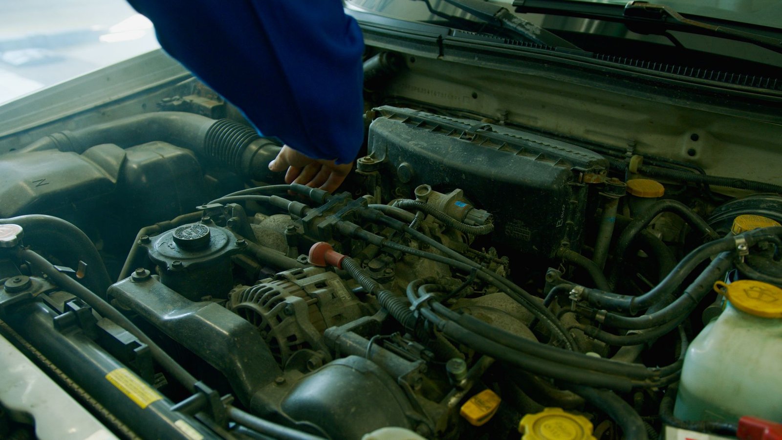 An alternator visible in a car engine bay during service
